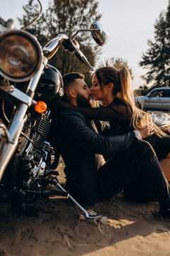 Evening walk of a biker and a girl on the river bank. Photoshoot at sunset.
