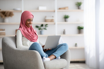 Obraz premium Portrait Of Young Black Muslim Woman In Hijab Using Laptop At Home