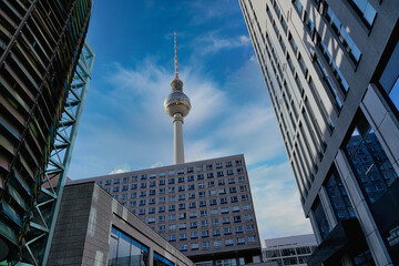 Der Berliner Fernsehturm aus einer Untersicht inmitten anderer Gebäude an einem sonnigen Maitag