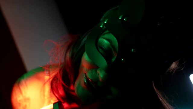 Portrait of a cute girl in a cat mask enjoying life with neon lights in a club