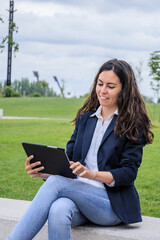 Young businesswoman using tablet and laughing in modern park