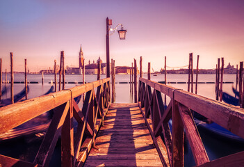 Pier with gondolas in long exposure in venice at sunset