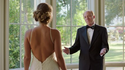 A father seeing his daughter in her wedding dress for the first time, hugging her with pride.