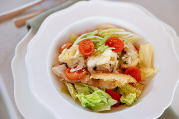 Caesar salad on a served table with bread croutons and fresh iceberg salad close-up. Fried chicken breast.