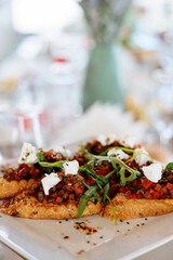 Bruschetta with baked vegetables, mushrooms and feta cheese. Garnished with arugula leaves and sprinkled with sesame seeds. Exit service catering, wine apetitizers.