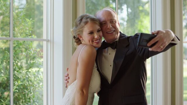Slow motion shot of a father and daughter taking selfies before wedding ceremony.