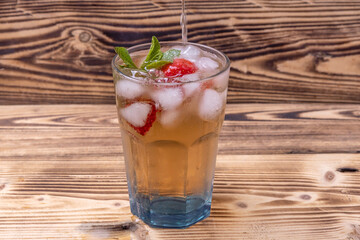 a glass of iced tea with strawberries and mint. soft drinks in the heat