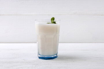 A glass of traditional Indian fermented milk drink lassi with mint on a light background  with copy space