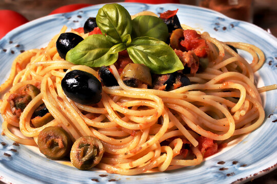 Delizioso piatto di spaghetti alla mediterranea con sugo di pomodoro, olive nere e verdi, basilico e origano.