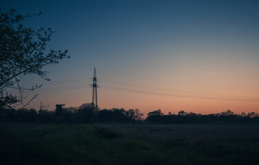 Fototapeta na wymiar Strommast für die Aufhängung einer elektrischen Freileitung bei Sonnenuntergang