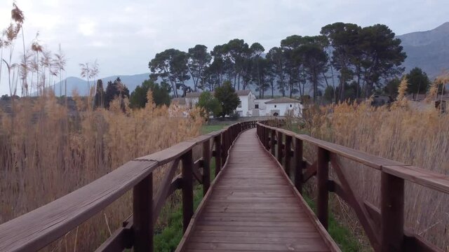 Paseo por puente de madera con vistas a casa rural y rodeado de paraje natural 