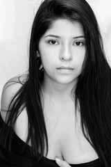 colorless portrait photo, latin woman with black hair and serious look, posing from front with white background