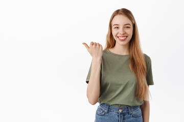 Your logo here. Smiling confident girl student pointing thumb left and looking determined, give advice, recommend this product, showing advertisement on copy space, white background