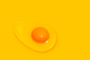 raw fried egg on yellow background