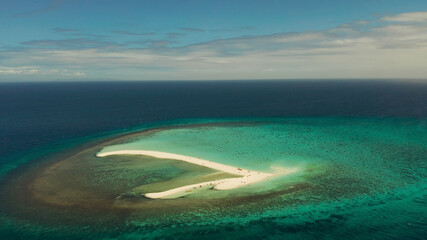 Tropical white island and sandy beach with tourists surrounded by coral reef and blue sea, aerial...