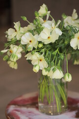 Bouquet of white ranunculus in glass vase.