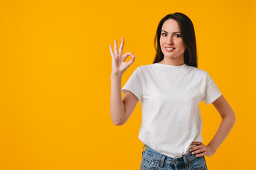 Confident trustful young latin-american woman showing okay gesture isolated on yellow background....