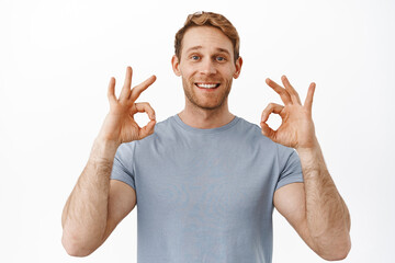 Yes alright. Smiling handsome redhead man with bristle, showing okay OK sign to support your idea,...