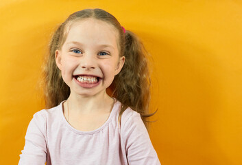 a little girl laughs on a yellow background, bright emotions in children