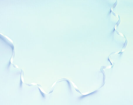 Delicate blue paper background with minimalist ribbon decor. Contrast and minimalism concept. Free space for your text.