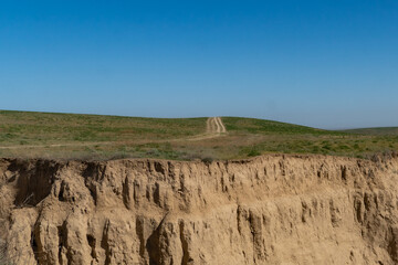 Endless steppe in the valley at the foot of the mountains, bathed in bright sunlight. Amazing view on  green mountains. mountain, covered with green trees, under a blue sky with clouds.