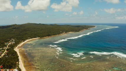 Coast of Siargao island, with palm trees and the ocean with waves and surf on a coral reef. Philippines