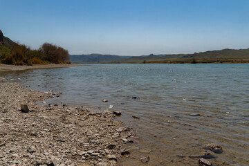 Aerial view of blue lake and green forests. View on the lake between mountain forest. Mountain lake with turquoise water and green trees. Aerial View. Drone shot over a beautiful mountain forest lake