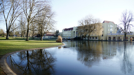 Jugendstil Kurhaus vor Seenfläche und kahlen Bäumen im Kurpark in Bad Hersfeld im Frühling mit Sonne ohne Menschen