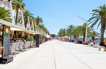 Splitska Riva Promenade tourist district with palm trees between the harbor and Diocletian Palace. Split, Croatia.  Lined with Restaurants and gift shops.