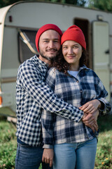 Romantic couple spending time together near trailer home. Handsome bearded man and beautiful woman enjoying company of each other. Traveling together with motor home.