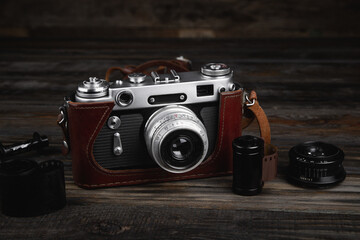 Vintage film camera with leather case on wooden table.
