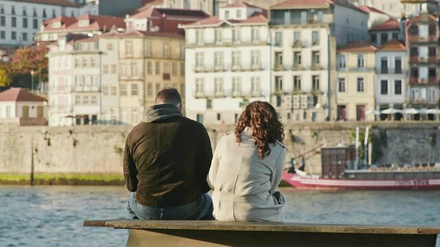 Porto, Portugal. Tourists rest by a river with tiled buildings behind. A man and a woman enjoying picturesque city views. High quality 4k footage