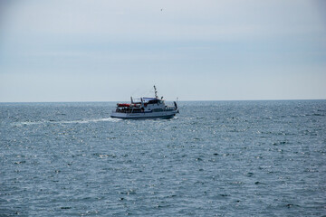 A tourist boat goes by the sea. A sailing yacht sails on the sea, a yacht is a dream.