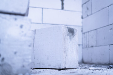 A large rectangular building aerated concrete block lies in a freshly built house close-up against the background of the walls