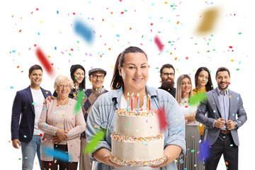 Corpulent young woman holding a birthday cake and people standing behind at a celebration