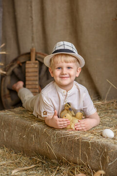 cute little boy in the hayloft with ducklings and hat