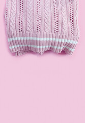 Woolen knitted pink sweater on paper background.