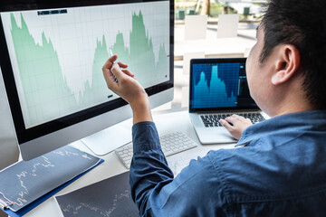 Businessman investor working in traders marketing and planning and analyzing pointing on the stock chart data presented and deal on a stock exchange to business profit