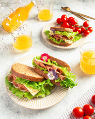 sandwich with ham, cheese and lettuce leaves on a gray background. Home cooking