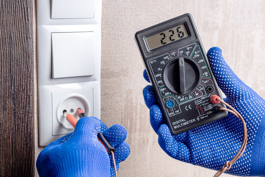 handyman electrician measuring wall outlet voltage at living room. outlet repair concept. test house wiring conceptual