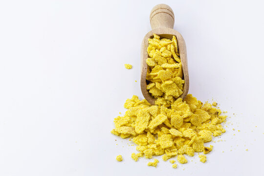 Toasted Cornmeal Flakes In Wooden Measuring Spoon, Isolated White Background