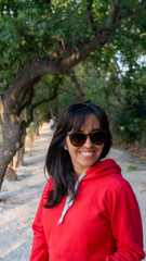 portrait of young woman wearing sun glasses in a green park at sunset