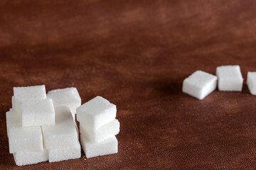 Sugar cubes with spoon top view on brown natural colored background texture with copy space,...