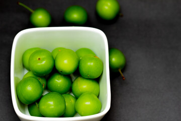 green plums in white bowl