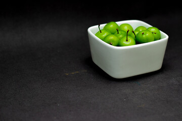 green plums in white bowl