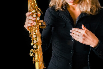 soprano saxophone in the hands of a girl on a black background