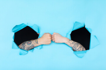 Through paper. Two hands with a tattoo holding each other