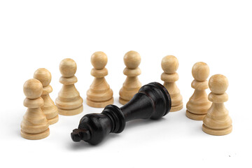 The black king lies in front of a row of white pawns on a white background. White wooden chess...