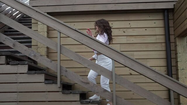 Beautiful young girl dancing on the street going down the stairs.
