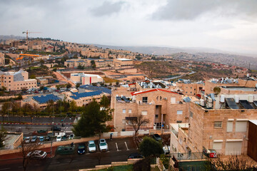 Fototapeta na wymiar view from the mountain to Jerusalem in cloudy weather. Cars, light stone houses, solar panels on rooftops